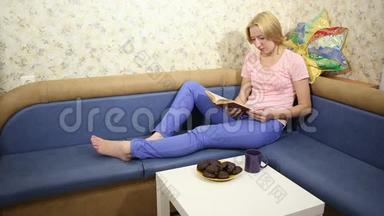 <strong>小</strong>姑娘坐在沙发上，看书，喝茶，吃巧克力棉花糖